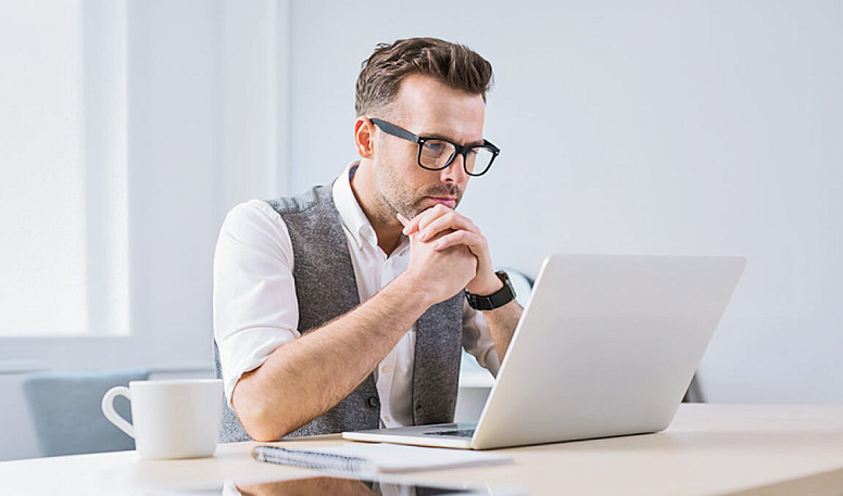 Man reviewing invoice or financial data on laptop, focused on payment and expense management