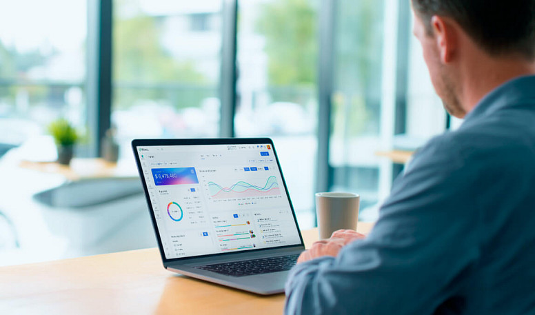 Small business owner analyzing performance dashboard with productivity and financial data on laptop