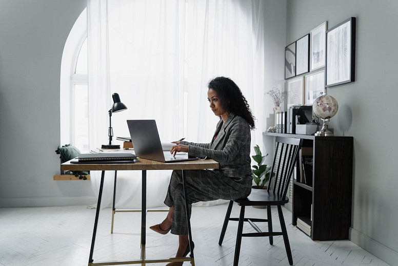 Businesswoman working on laptop in home office managing finances and tasks