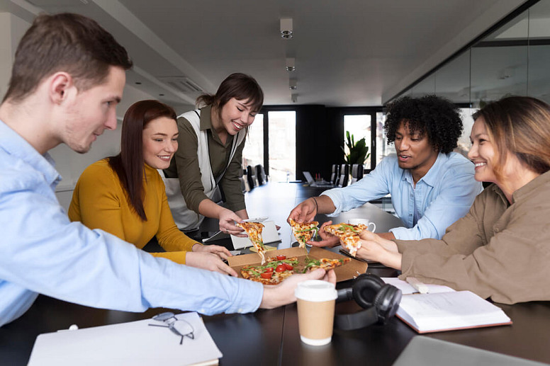 Un equipo está comiendo pizza en la oficina